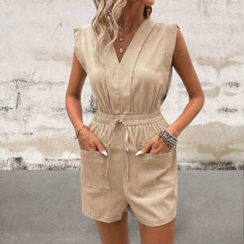 Woman wearing a beige romper against a textured wall.