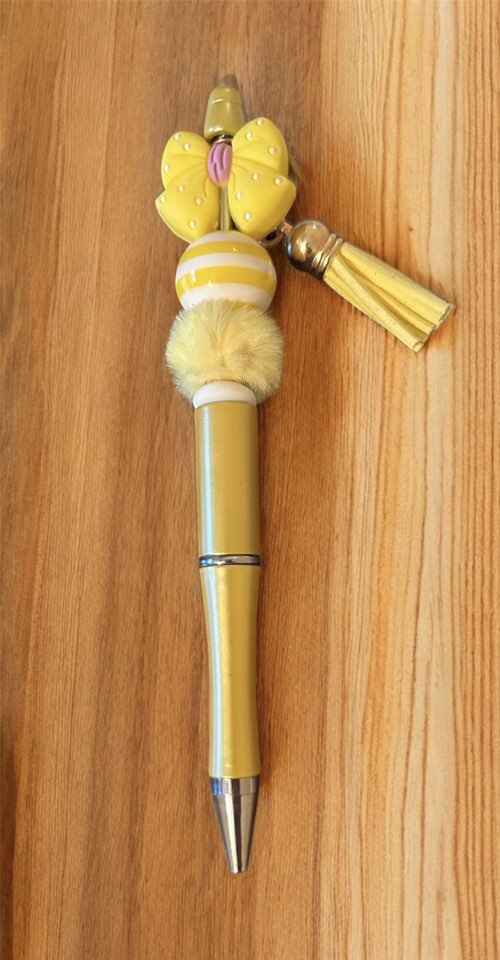 Decorative pen with yellow accents and tassels 