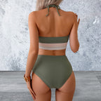 Person wearing a green bikini set against a textured gray wall.