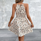 Woman wearing a leopard print dress against a gray concrete wall.