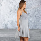 Woman wearing a gray dress against a textured gray wall.