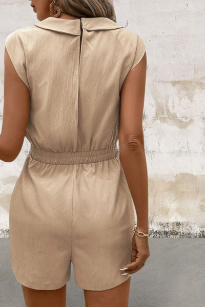 Person wearing a beige romper against a textured wall.