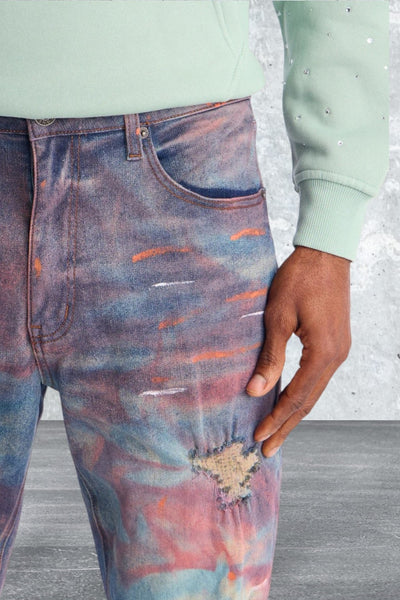 Close-up of a person wearing tie-dye jeans with a light green sweater.