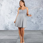 Woman wearing a gray dress against a textured gray wall.